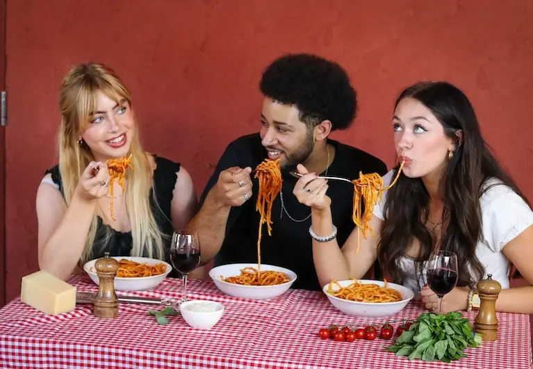 Young people enjoying eating pasta mobile